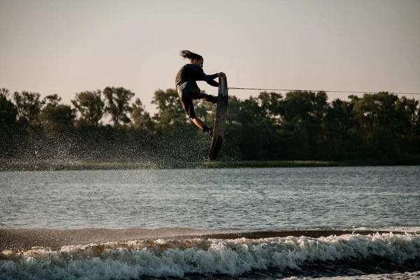 Wspaniały widok człowieka energii trzyma linę i skacze wysoko na wakeboard — Zdjęcie stockowe