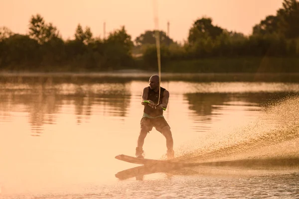 Homme sportif adulte tient la poignée de câble et équilibre avec un wakeboard sur l'eau — Photo
