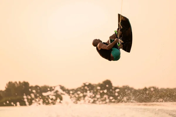 Człowiek skacze i odwraca na wakeboard na tle nieba. — Zdjęcie stockowe