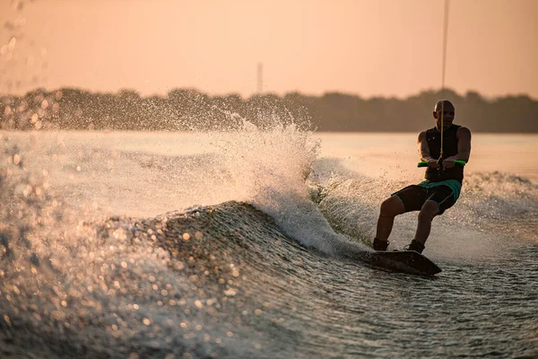 Grande vista di spruzzi d'onda e l'uomo muscolare energicamente equitazione wakeboard. — Foto Stock