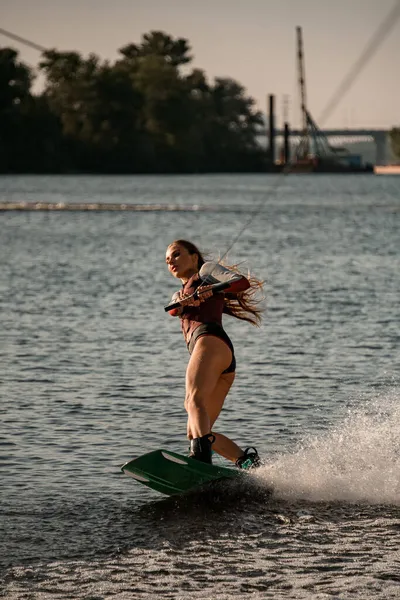 Vacker aktiv kvinna håller rep och balansera på våg på wakeboard. — Stockfoto