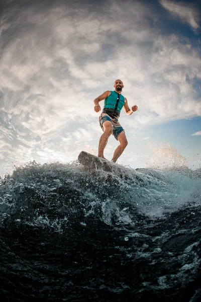 Pria atletik wakesurfer aktif menyeimbangkan on wakeboard sepanjang gelombang sungai — Stok Foto