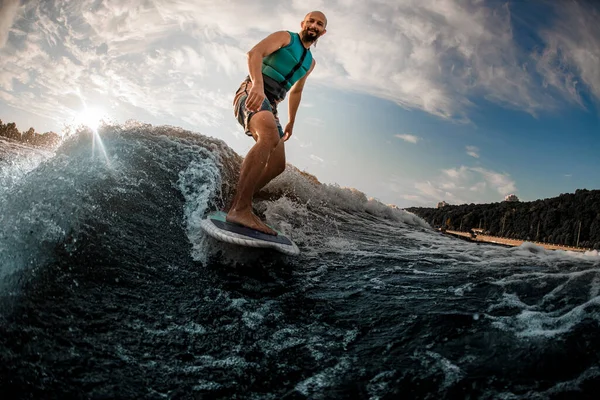 夏日快乐活泼的男人在蓝色的水里的一块木板上冲浪 — 图库照片