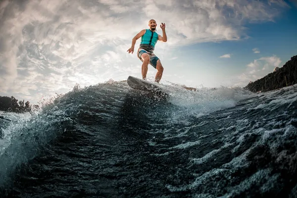 Pria ceria wakesurfer bersenang-senang dan menyeimbangkan diri di atas papan di sepanjang gelombang sungai — Stok Foto