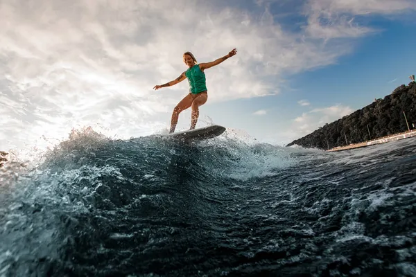 Femme souriante s'amusant wakesurf et équilibrage sur la planche sur la vague de la rivière contre le ciel bleu — Photo