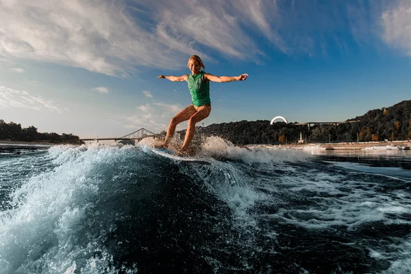 Femme heureuse équilibrant énergiquement sur la vague sur la planche de wakesurf au jour ensoleillé. — Photo