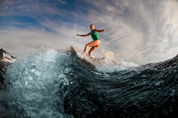 女性の豪華な景色が波打つ波の上でボードに乗って. — ストック写真