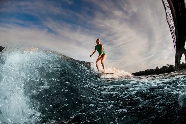 Storslået udsigt over kvinde wakesurfer ridning ned på brættet på sprøjt bølge. - Stock-foto