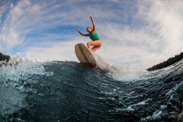 Energia női wakesurfer ugrás egy ébrenléti fórumon fröccsenő folyó hullám ellen ég — Stock Fotó