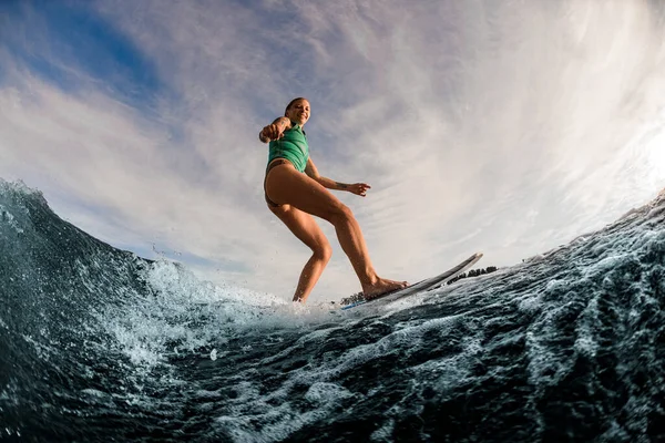 Superbe vue de sourire femme humide wakesurfer chevauchant la vague éclaboussante bleue — Photo
