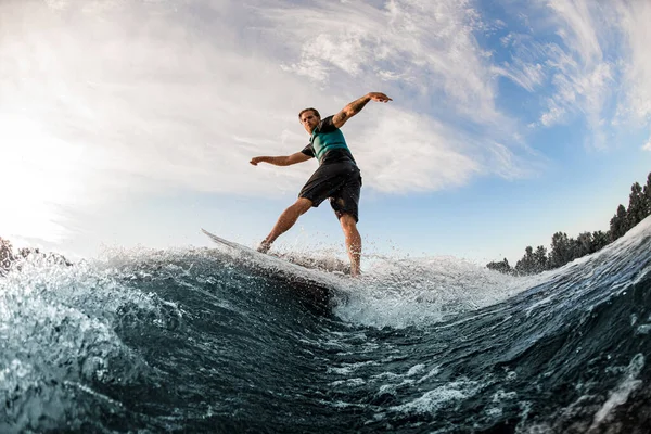 Jeune homme équilibrant énergiquement sur la vague sur la planche de wakesurf sur la vague éclaboussante. — Photo