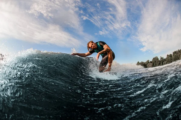 Atlético hombre wakesurfer divertirse y montar en salpicadura río ola contra azul cielo —  Fotos de Stock