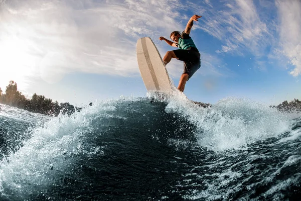 Молодий спортсмен розважається і стрибає на дошці на річковій хвилі — стокове фото
