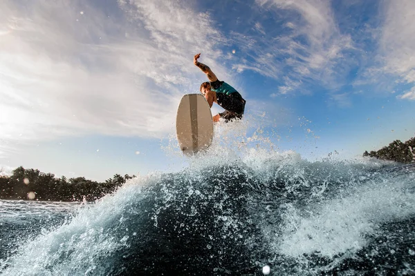 Energía masculina wakeboarder realiza truco en saltar usando olas altas por el río —  Fotos de Stock