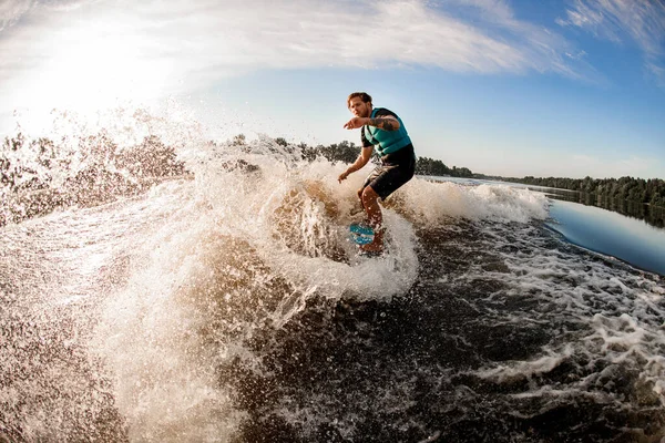 Superbe vue sur les éclaboussures de vague de rivière et l'homme athlétique wakesurfer équitation sur elle — Photo