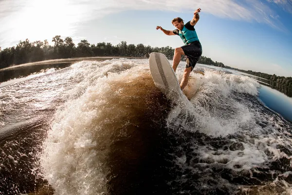 Активний хлопець пробуджує стрибок на дошці пробудження вниз по річковій хвилі — стокове фото