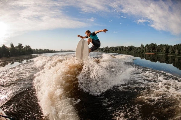 Energia wakesurf cavaliere saltando sulle onde del fiume contro il cielo e gli alberi — Foto Stock