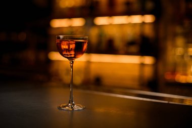 Önünde güzel bir şarap kadehi, masada içki.