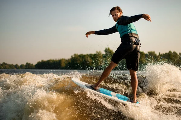 Pria basah yang sehat energik menyeimbangkan pada gelombang di papan wakesurf. — Stok Foto