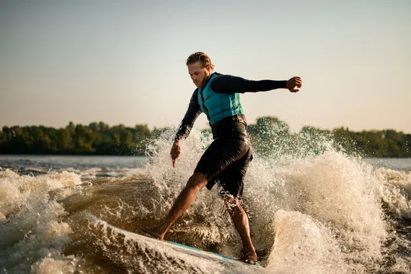 Mann balanciert energisch auf Welle auf Wakeboard. — Stockfoto