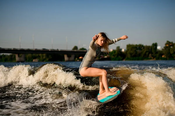 Actieve flexibele vrouw energiek balanceren op grote spetterende golf op wakesurf board. — Stockfoto