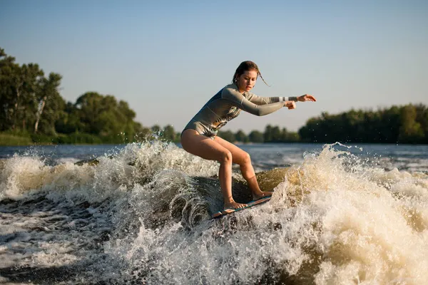 Aktif, esnek bir kadın. Uyandırma tahtasındaki büyük su sıçrama dalgasında ustaca dengede duruyor.. — Stok fotoğraf