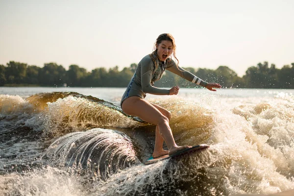 Surpris femme humide wakesurfer équitation sur éclaboussures vague par une journée chaude — Photo