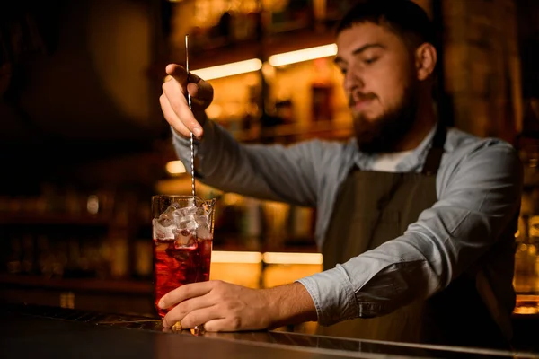Рука бармена мягко перемешивая холодный коктейль с ложкой в стакане смешивания о — стоковое фото