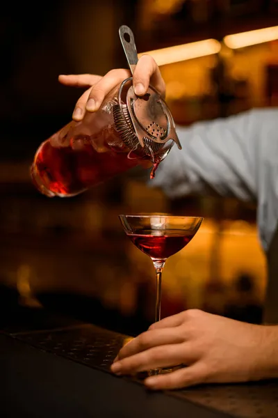 Vue rapprochée du verre à vin dans lequel verser la boisson froide de la tasse de mélange — Photo