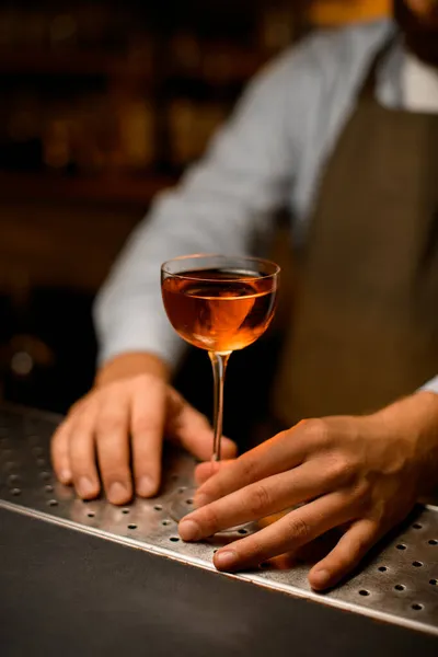 Schönes Weinglas mit alkoholischem Getränk auf Stahlstangenoberfläche und männliche Hand hält es. — Stockfoto