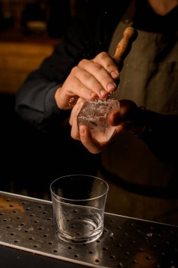 Erkeklerin elinde buz kırıcı ve bardakla ezilen büyük bir buz küpü.