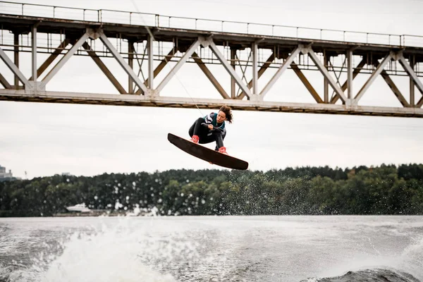 Jeune femme fait un saut extrême sur le wakeboard, il ya beaucoup d'éclaboussures d'eau autour — Photo