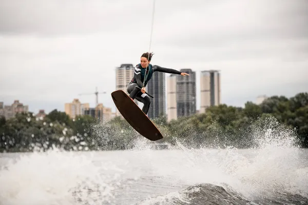 Attrayant jeune femme wakeboarder fait magistralement astuce et saut en hauteur sur l'eau de la rivière — Photo