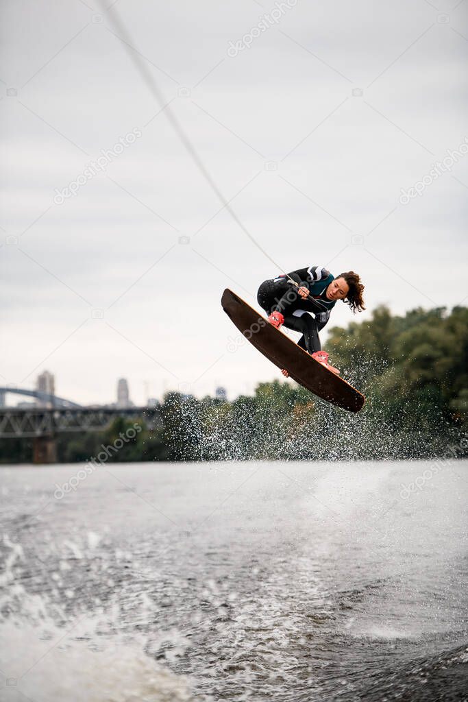 female wakeboarder makes high jumps over splashing water