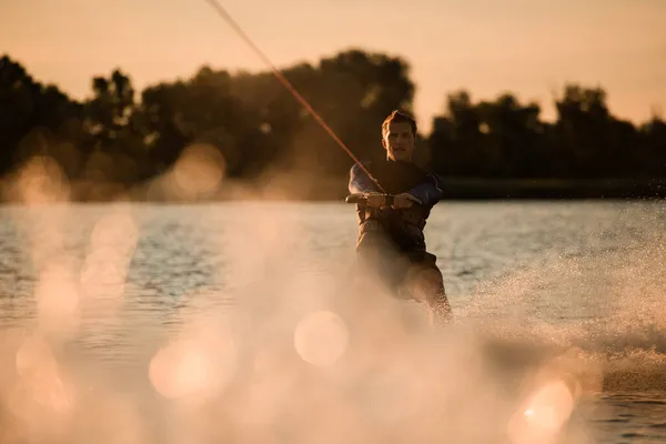 Vue merveilleuse de l'homme attrayant tenant la corde et chevauchant énergiquement wakeboard sur éclaboussant vague de rivière. — Photo