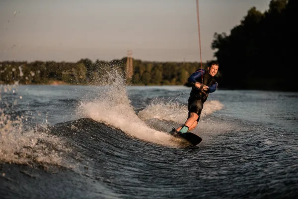 Widok sportowca trzyma linę i jedzie w dół fali na wakeboard — Zdjęcie stockowe