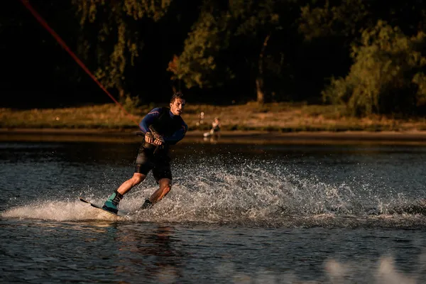 Vue de l'homme athlétique tenant la corde et montant sur wakeboard — Photo