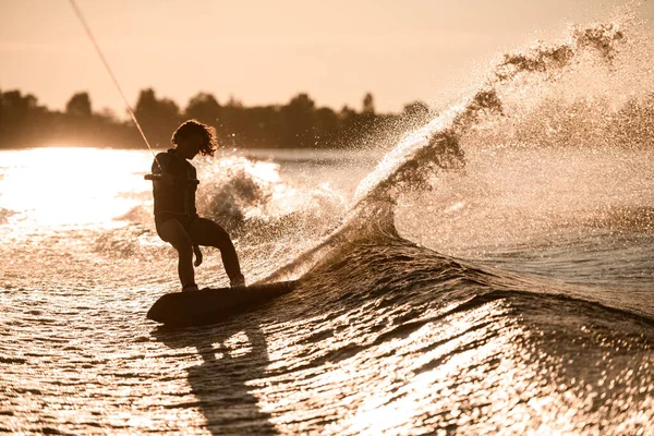 Vue imprenable sur la silhouette du cavalier féminin tenant la corde et descend sur wakeboard sur la vague éclaboussante. — Photo