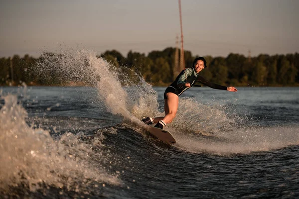 Femme active souriante tenant la corde et descendant la vague sur wakeboard — Photo