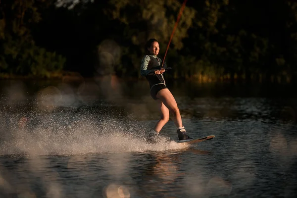Superbe vue de femme heureuse tient la corde et magistralement équitation wakeboard sur éclaboussure de l'eau de la rivière — Photo
