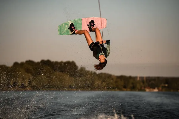 Beautiful view of female rider holding rope and making jump on wakeboard. Water sports activity. — Stock Photo, Image