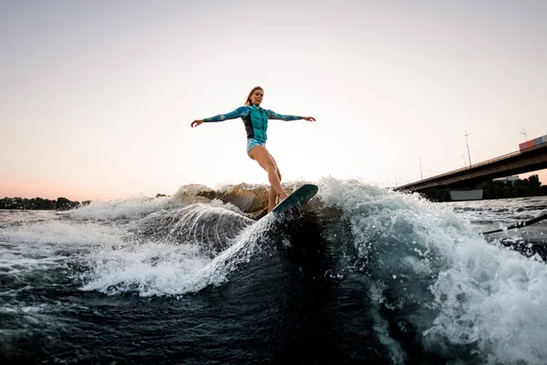Beautiful woman energetically balancing on great splashing wave on wakesurf. — Stock Photo, Image