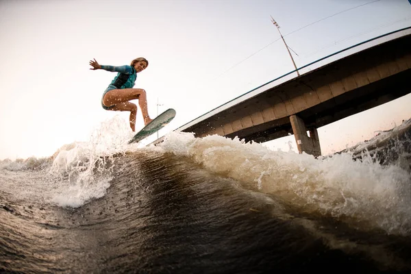 Güzel, atletik bir kadın ustalıkla nehrin dalgalarından atlıyor.