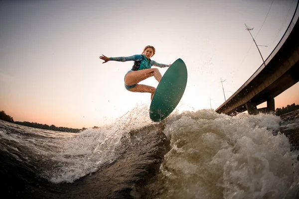 Energía femenina wakesurfer hábilmente saltar en wakesurf por la ola del río — Foto de Stock