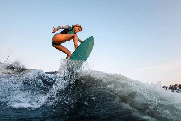 Aktive Wakesurferin springt gekonnt auf Wakesurf die Flusswelle hinunter — Stockfoto