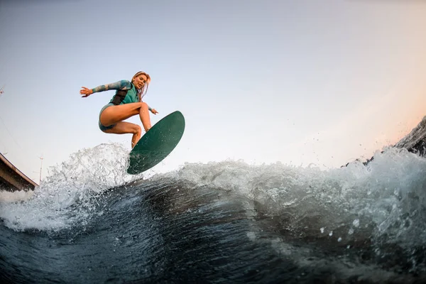 Energia mulher wakesurfer habilmente pulando no wakesurf para baixo da onda do rio — Fotografia de Stock