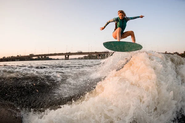 Femme wakesurfer sautant habilement sur wakesurf par-dessus grande vague de rivière éclaboussure — Photo