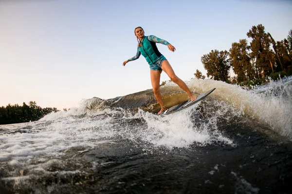 Mujer dedicada al deporte acuático y magistralmente tratando de pararse en salpicadura ola en wakesurf —  Fotos de Stock