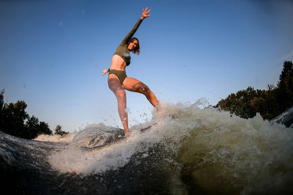 Femme athlétique saine équilibrage sur planche de wakesurf sur la vague de la rivière — Photo