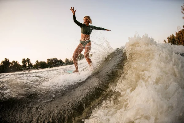 Alegre joven mujer cabalgando wakesurf en salpicaduras de agua del río. Deportes acuáticos activos —  Fotos de Stock